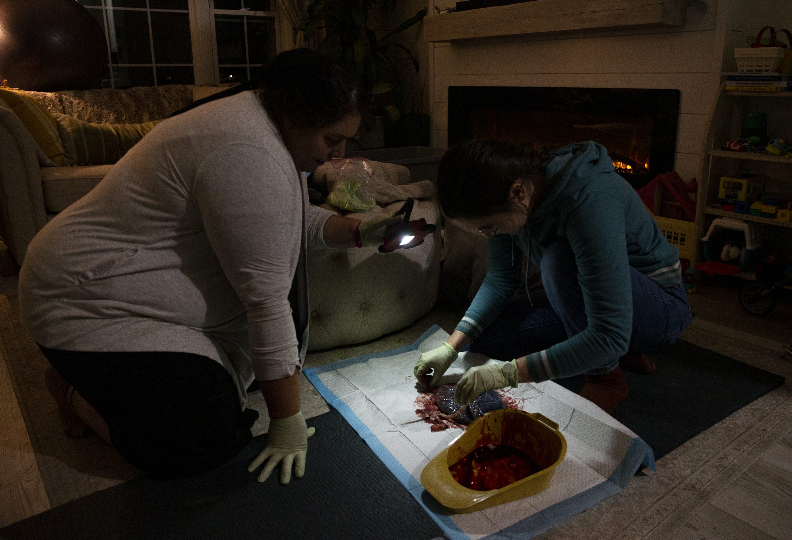 Senior certified professional midwife students Louise Zook, left, and Samantha Woolman check the placenta Dec. 5, 2022, of Chelsey Montgomery-Gusta after her home birth in Riverside.