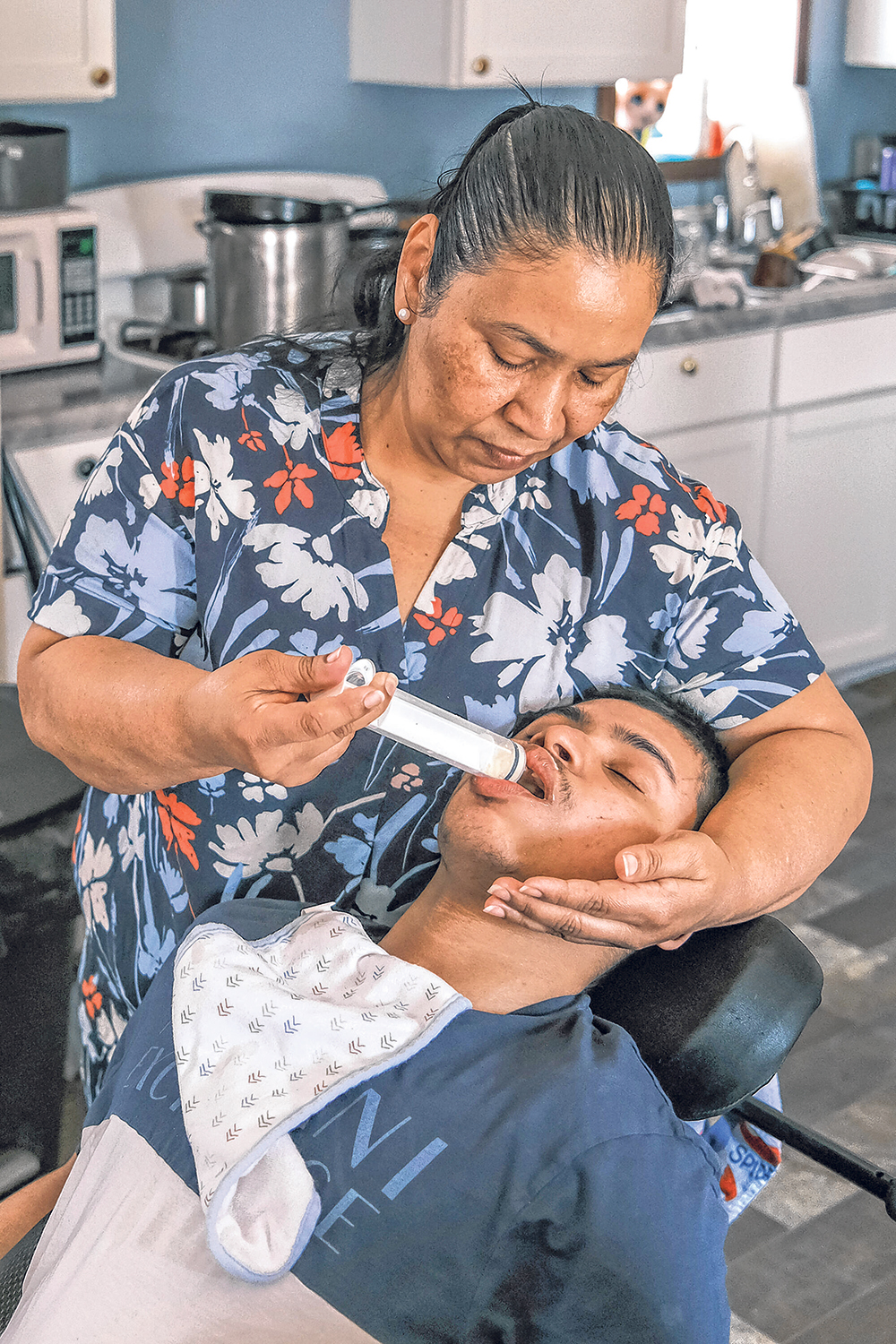 Maria Davila Hererra feeds her son, Christian Davila Reconco, 20, on April 12 at her home in Iowa City. Davila Reconco was born with physical and developmental disabilities.
